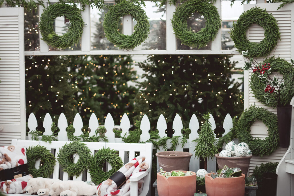 Wreaths and garlands display with white accents and picket fence detail