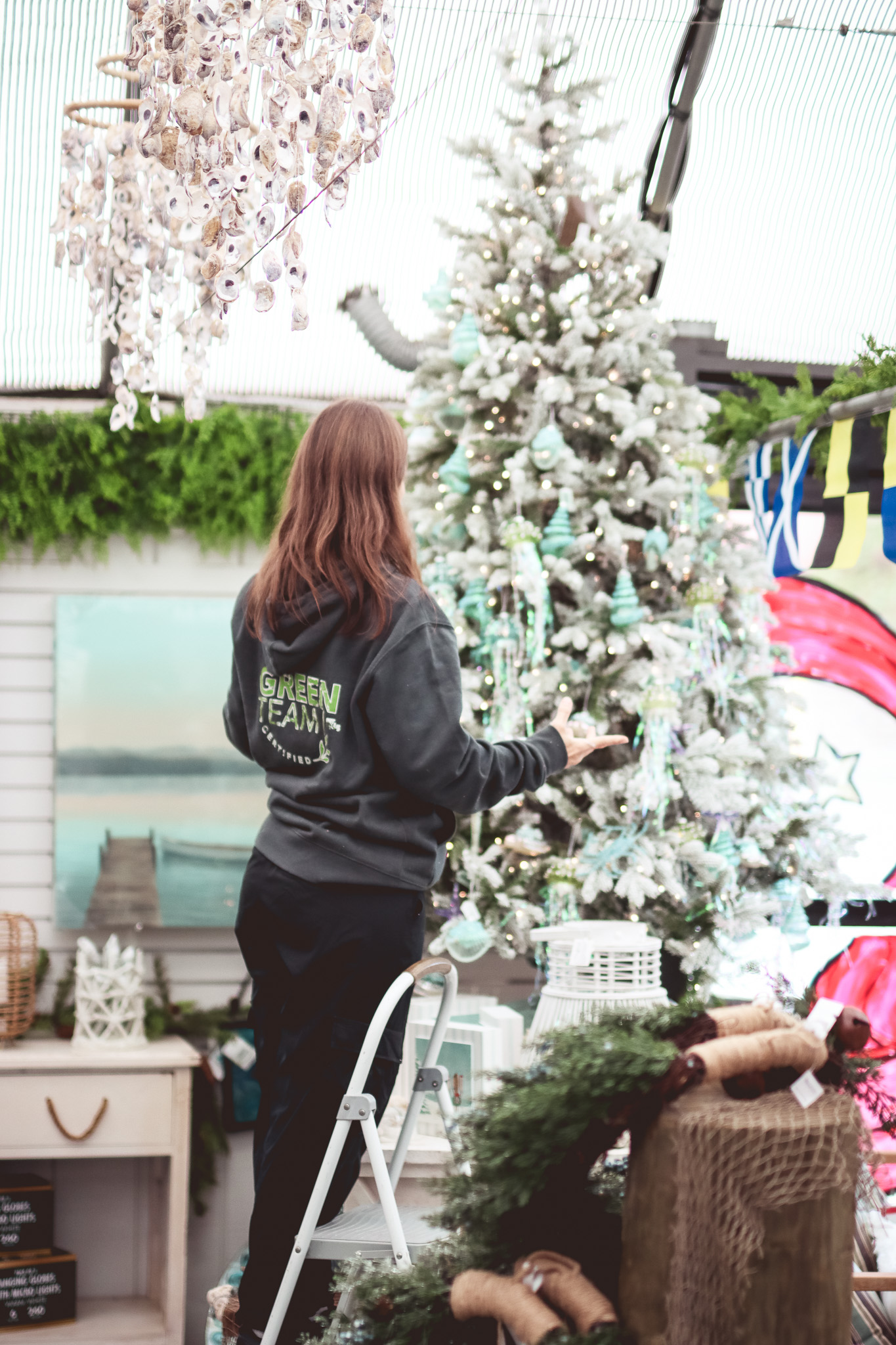 Green Team member decorating coastal lifelike tree in greenhouse